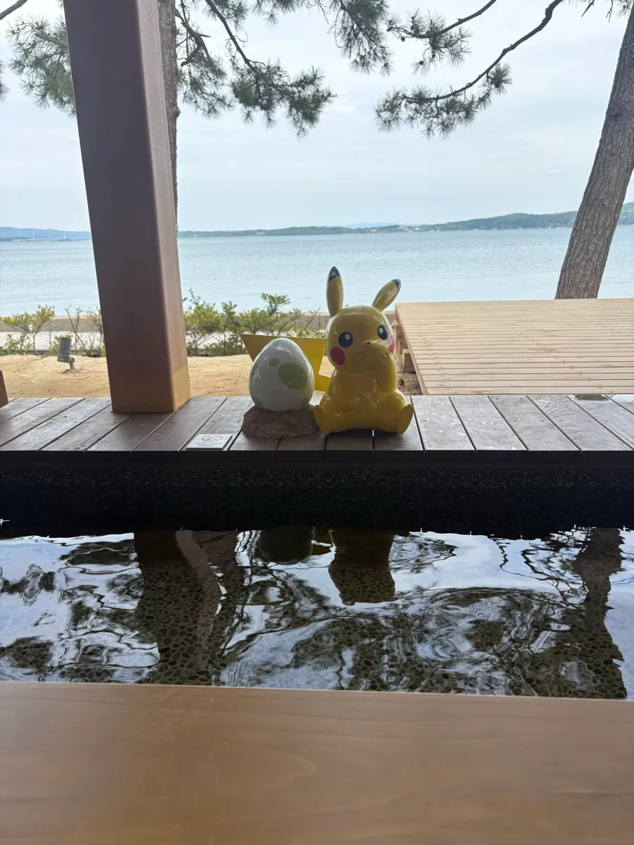ピカチュウのフィギュア越しに見る七尾湾の眺め。足湯の水面に空が映る