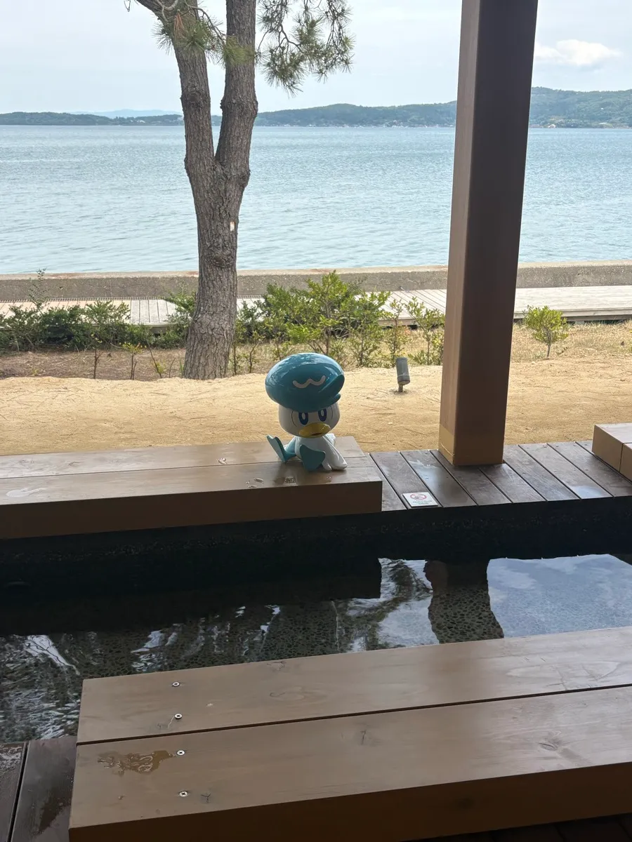 クワッスのフィギュアと足湯、奥には七尾湾の海が広がる